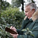 Photo of a senior man writing in a notepad while outdoors: Thumbnail for an article on essential skills for an environmental researcher